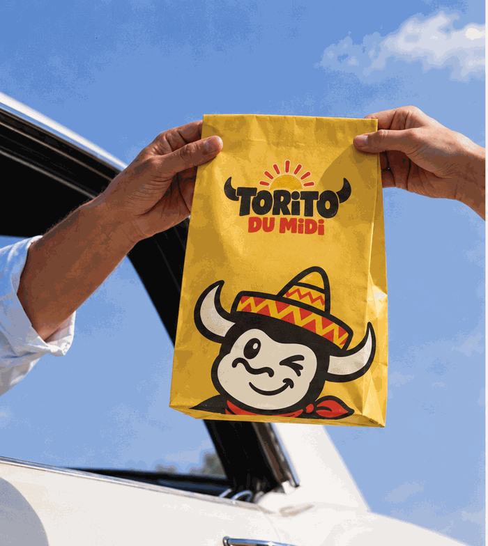 Un sac Torito du Midi tendu par la fenêtre d'une voiture, prêt à emporter